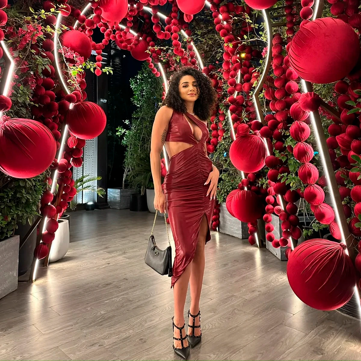 Larissa in a burgundy dress beneath a red floral installation